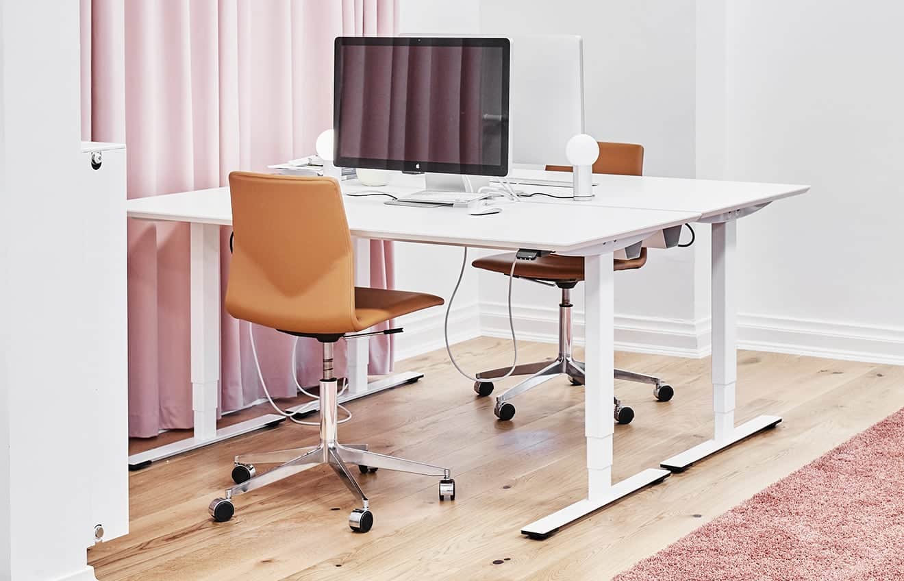 A white desk with a pink curtain and a computer.