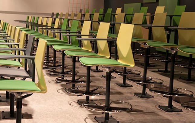 A row of green and yellow chairs in a classroom.