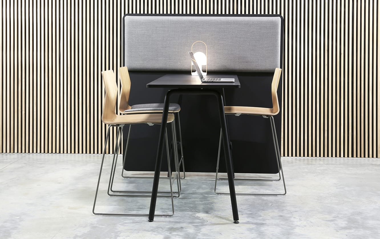 A black standing height table with two chairs in front of it.
