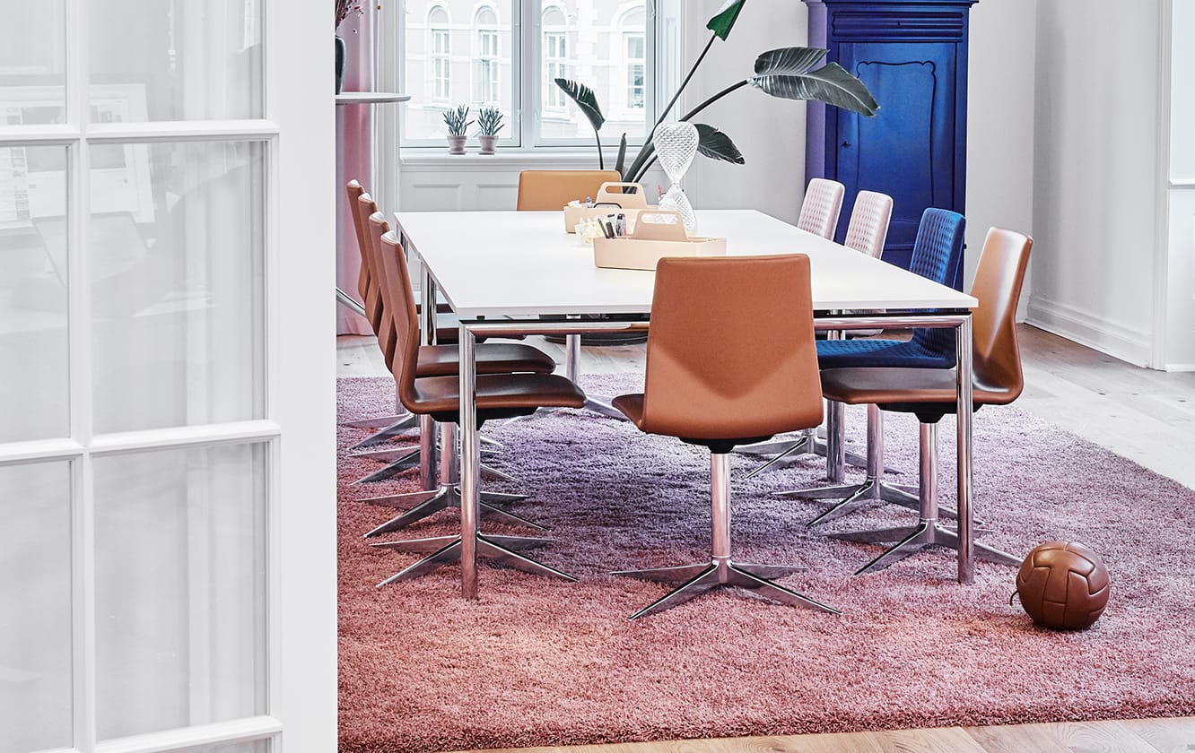 A dining table and chairs in a room with a pink rug.