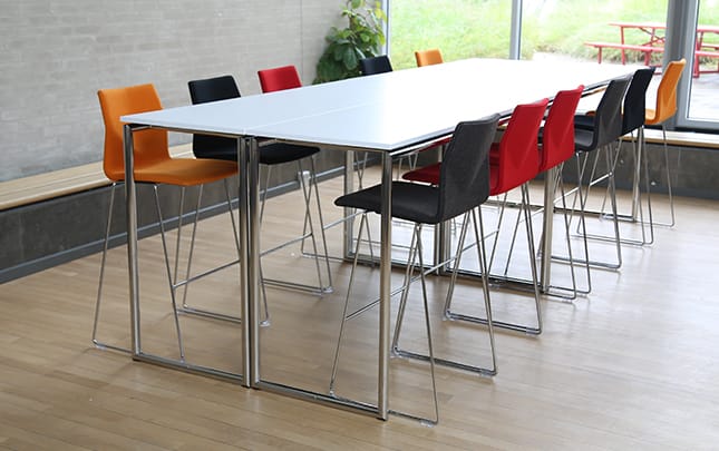 A table with counter chairs in a conference room.
