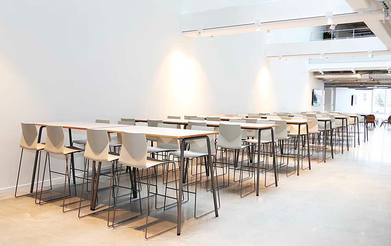 A long line of standing height tables and counter chairs in a room.