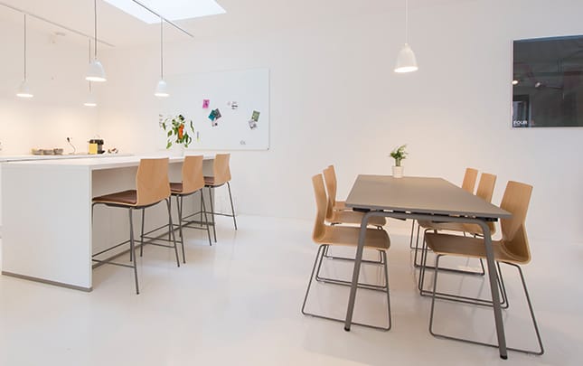 A white kitchen with a standing height tables and counter chairs.