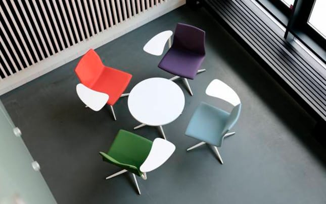 A group of colourful chairs arranged around a table.