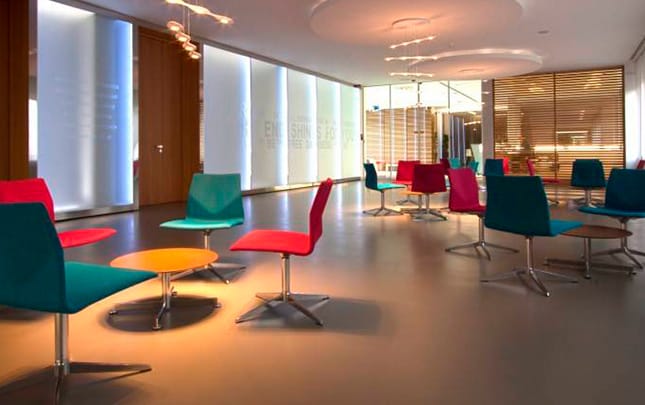 A lobby with colourful chairs and a glass wall.