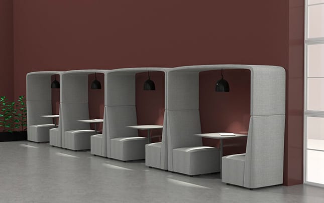 A row of office work booths in a room with a red wall.