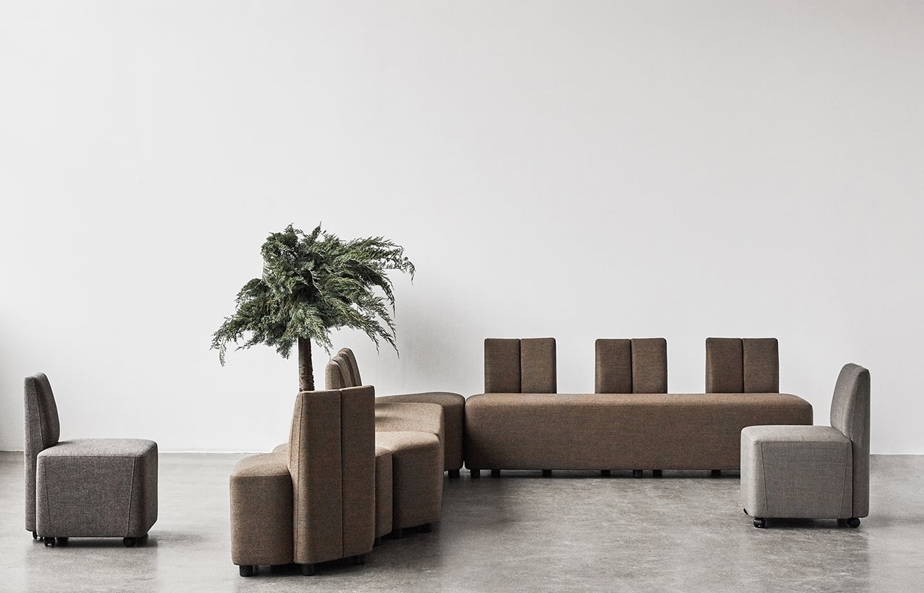 A group of office sofas in a room with a plant in the middle.