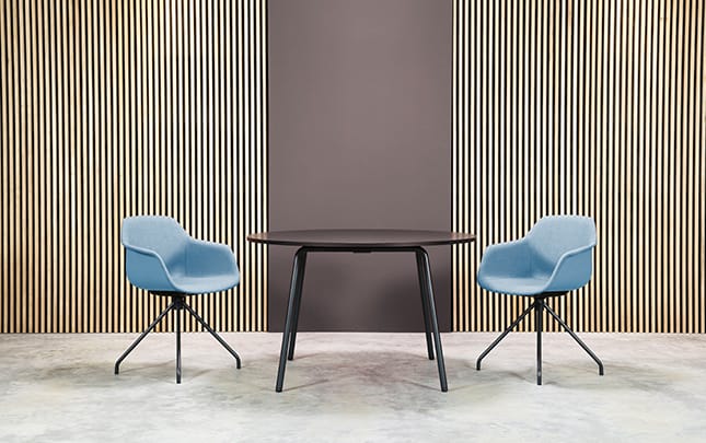 Two chairs and a table in front of a wooden wall.