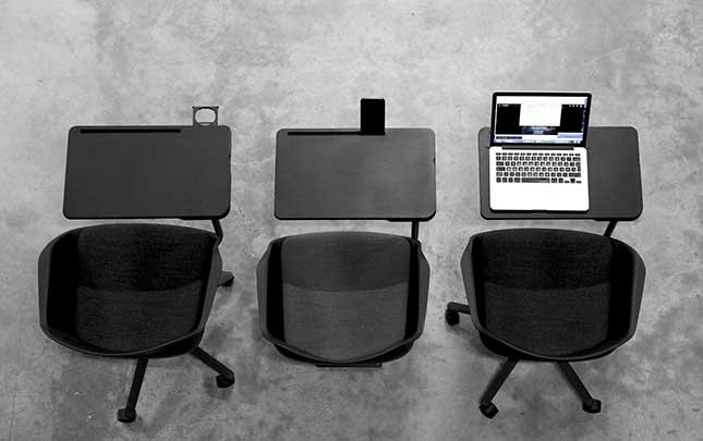 three chairs with desk attached and a laptop.