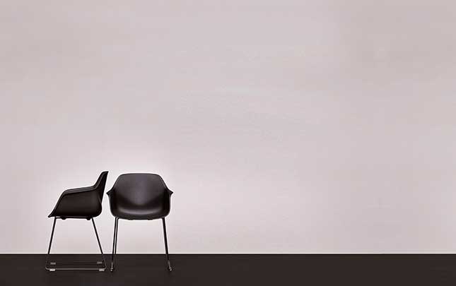 Two black chairs in front of a white wall.