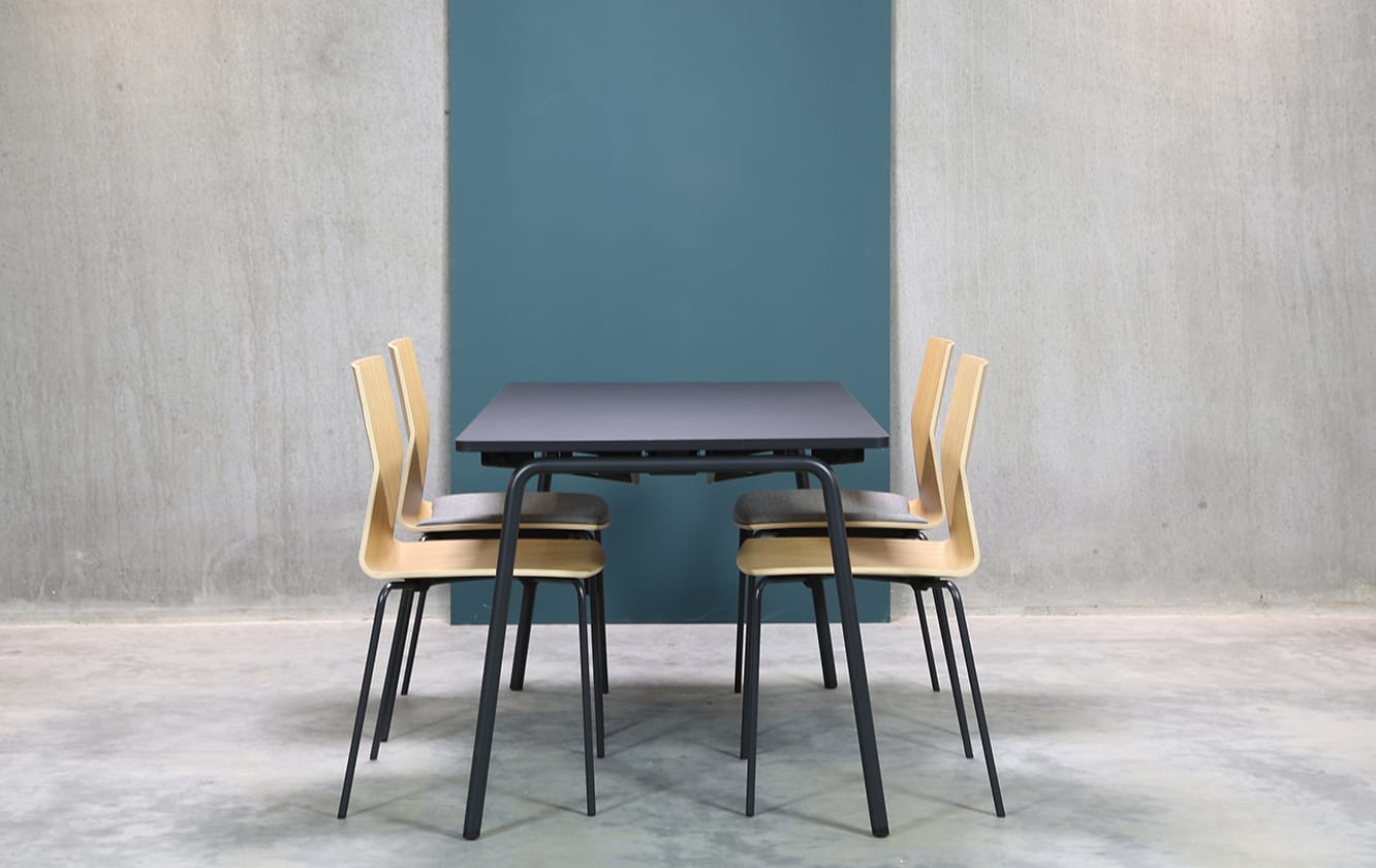 A table with four chairs in front of a blue wall.