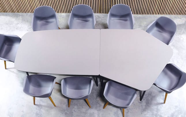 A group of grey chairs around two office tables that have been pushed together to form a conference table