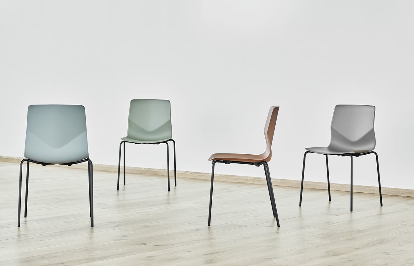 Four different coloured chairs in an empty room.