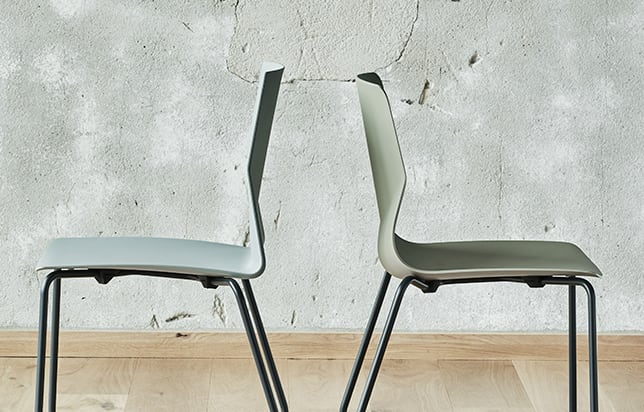 Two chairs sitting next to each other in front of a wall.