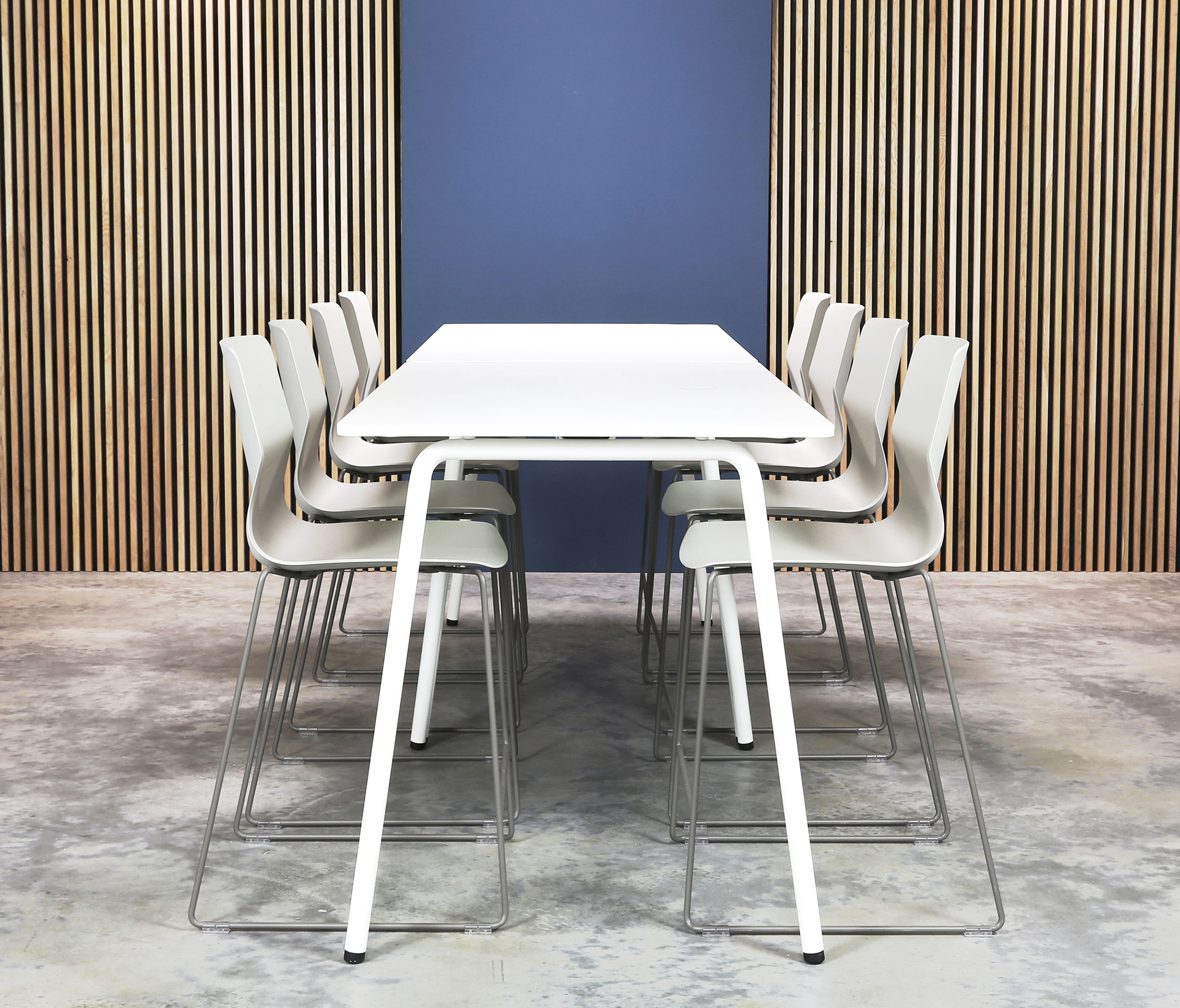 A white standing height tables and chairs in front of a wooden wall.
