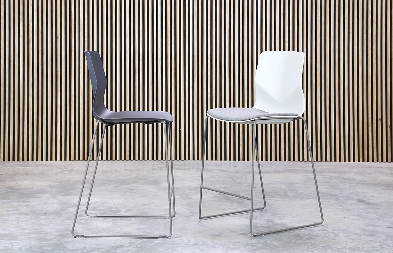 Two counter chairs in front of a wooden wall.