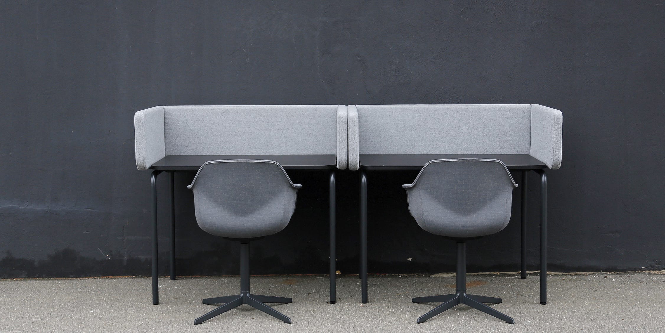 Two grey chairs and desk workstations against a wall.