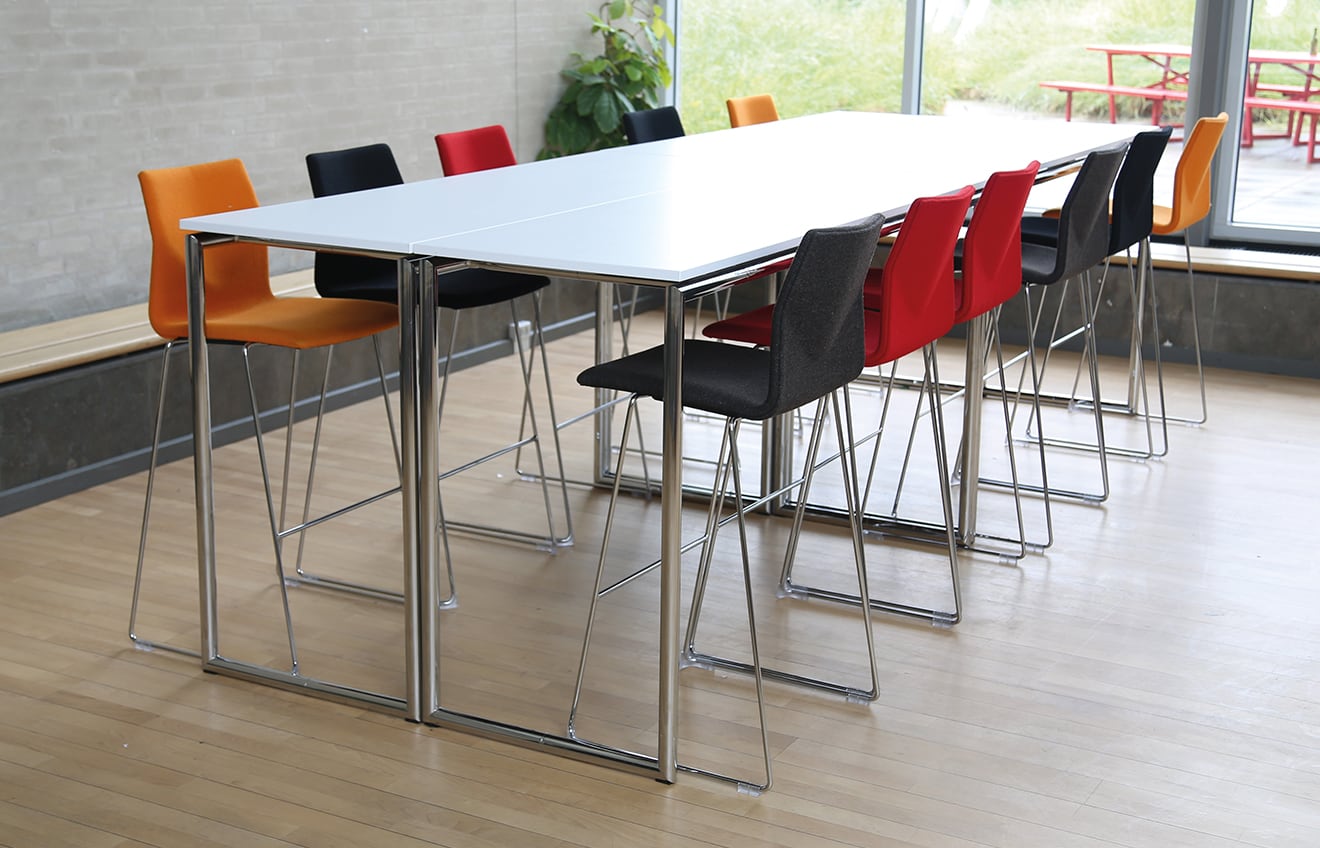 A white conference standing height table with counter chairs around it.
