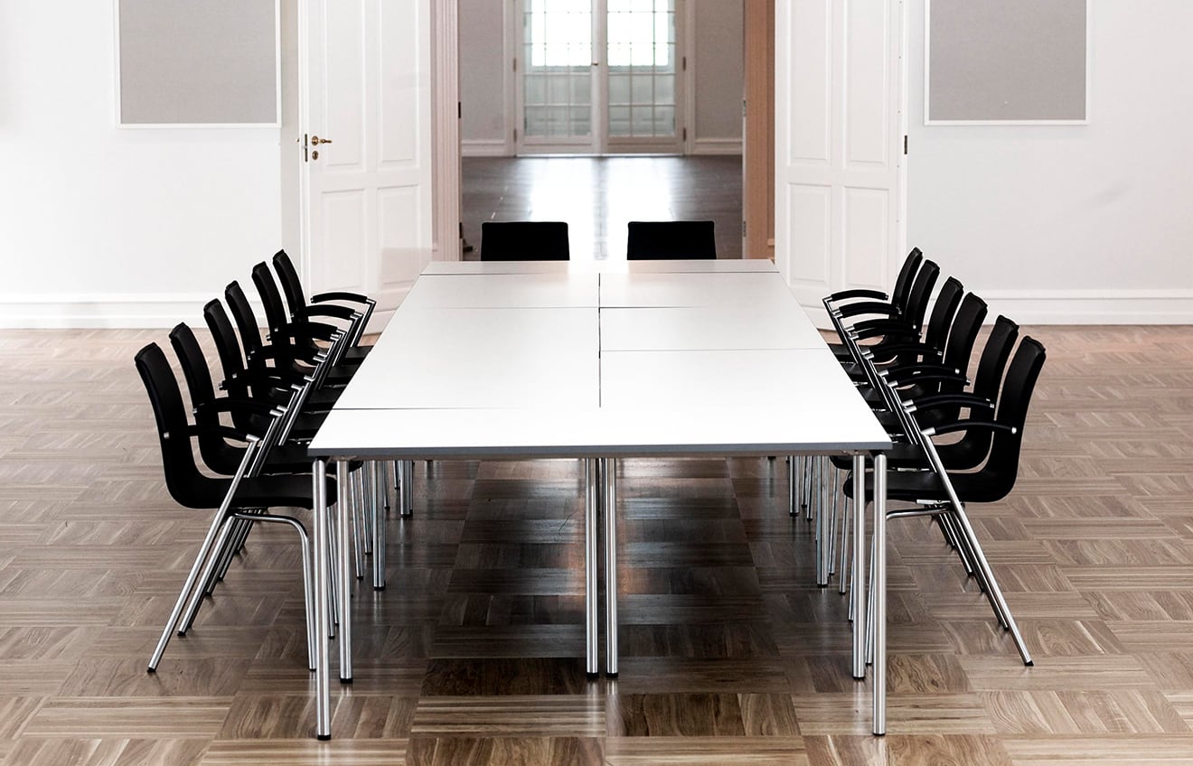 Office tables pushed together to make a conference table in a room with black chairs.