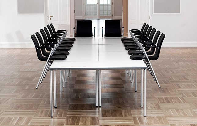 Office tables pushed together to make a conference table in a room with black chairs.