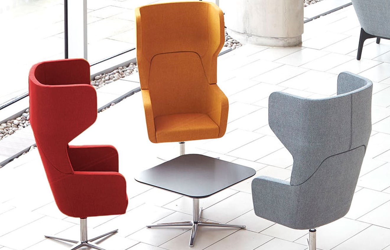 Four lounge chairs for offices and a table in a lobby.