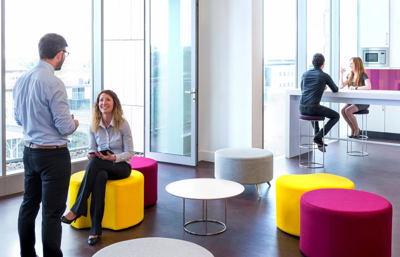 A group of people sitting in a brightly coloured office.