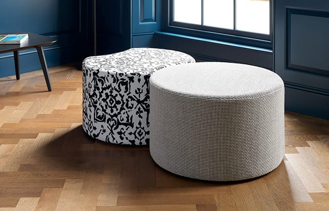 A black and white ottoman sitting on a wooden floor.