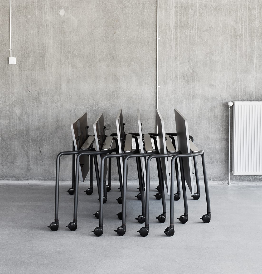 A group of folded tables on wheels in a concrete room.