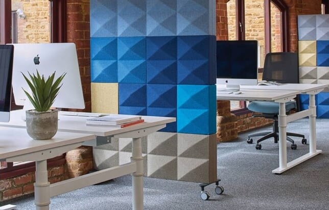 An office with blue and white desks and chairs and acoustic panels for offices