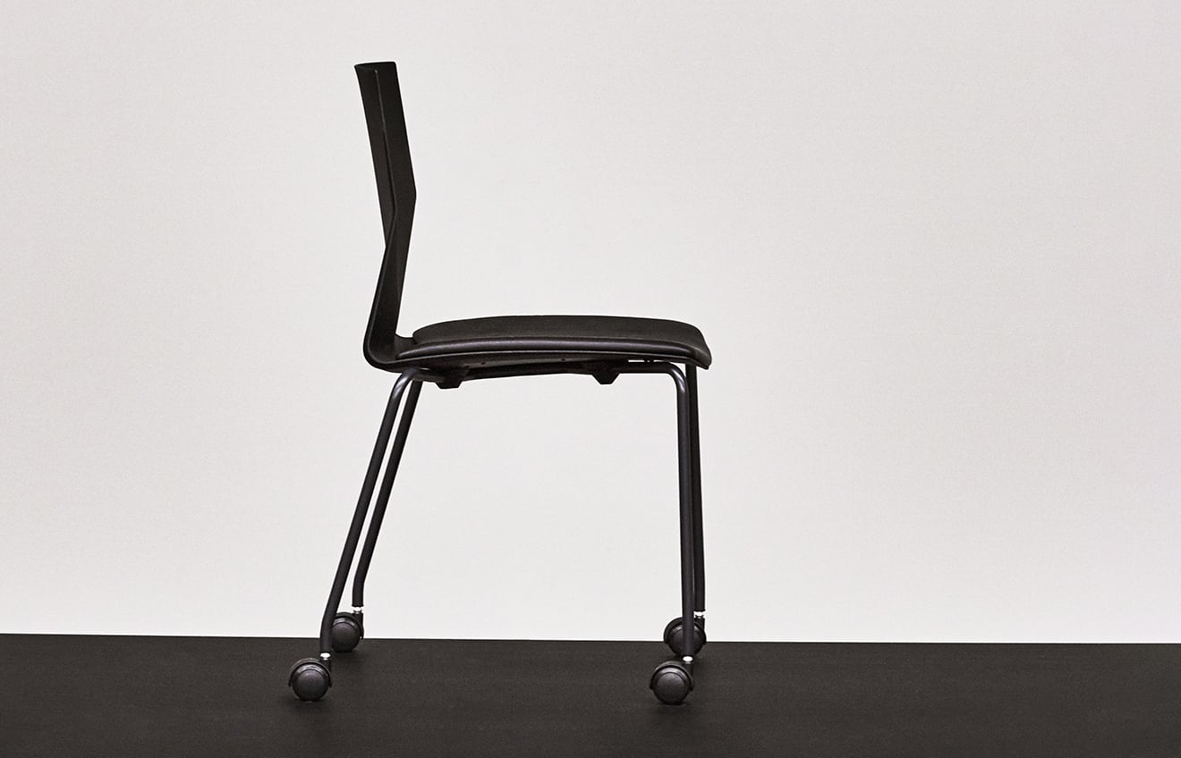 A black chair with wheels on a black surface.