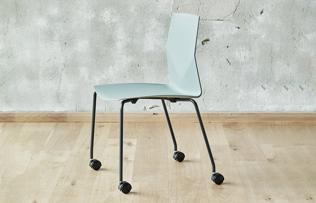 A light blue chair on wheels in front of a wall.