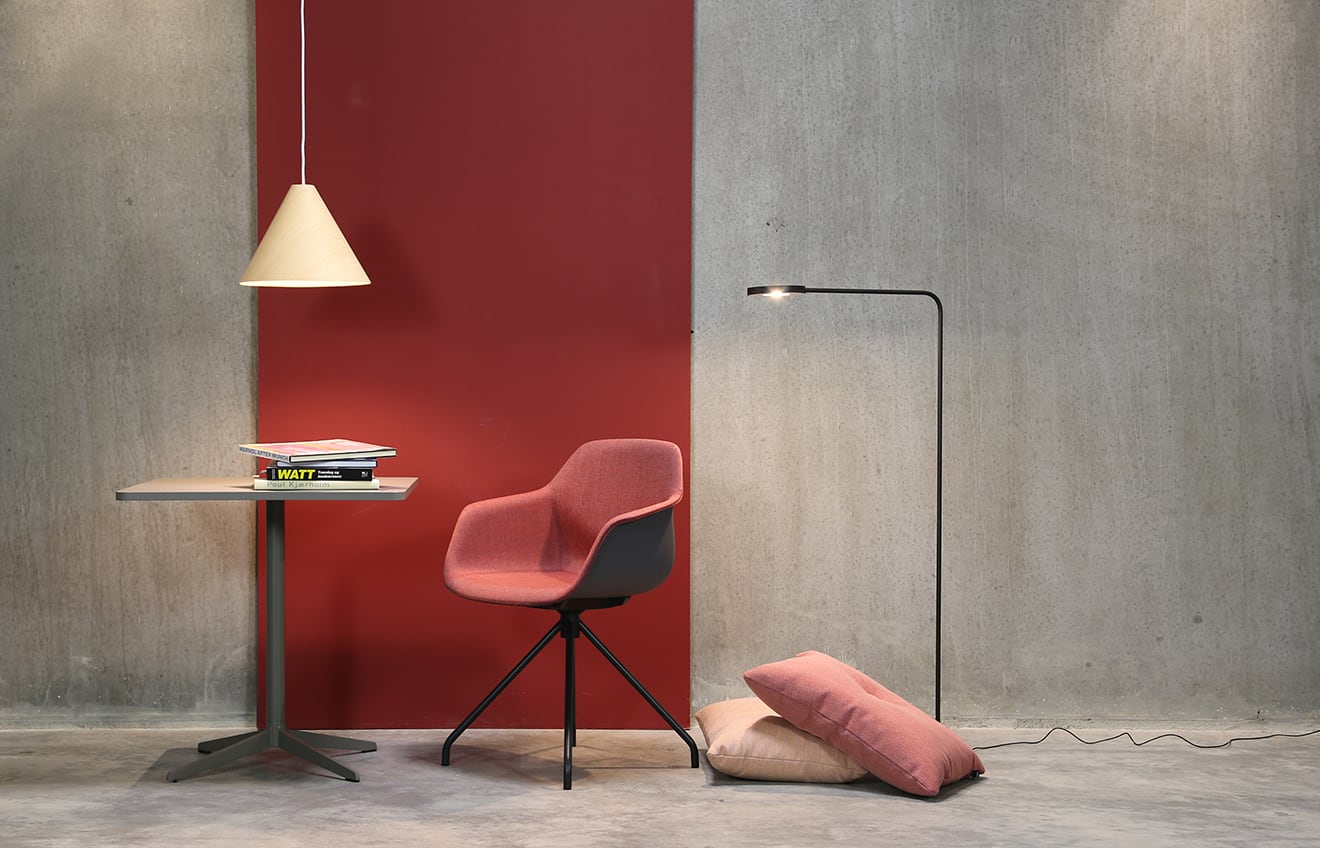 A desk, chair and lamp in a room with a red wall.