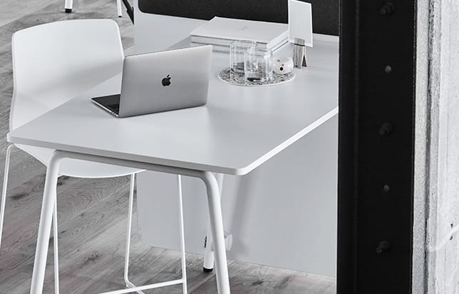 A white desk with a laptop on it.