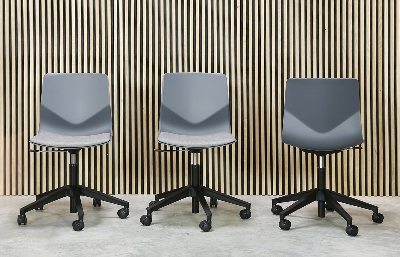 Three grey office chairs in front of a wooden wall.