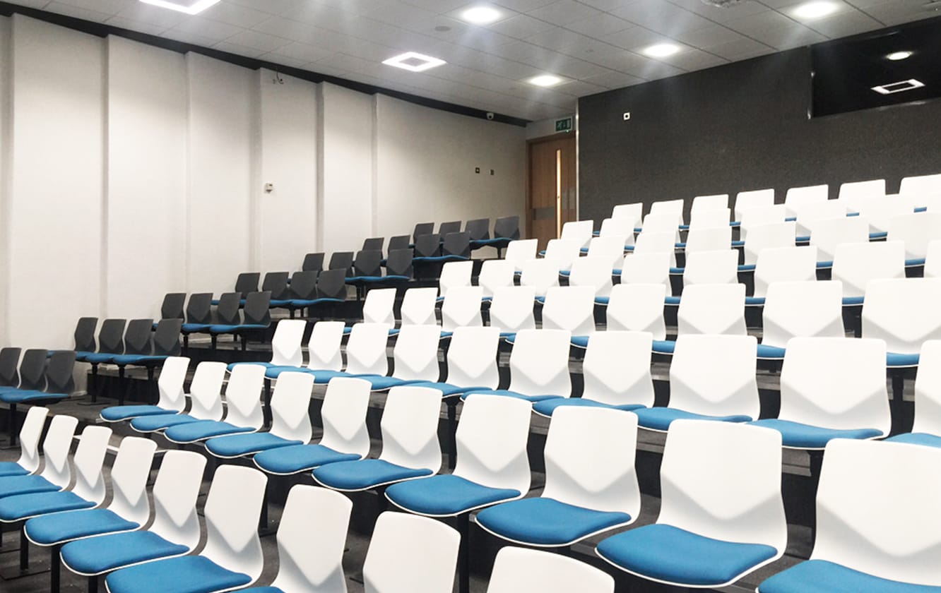 A lecture hall with rows of chairs and blue seats.