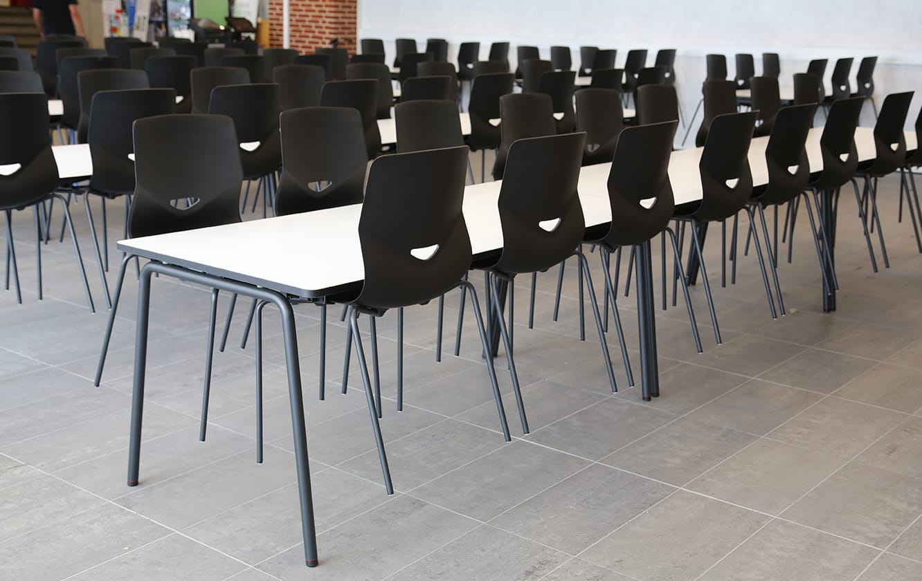 A long row of black chairs in a classroom.