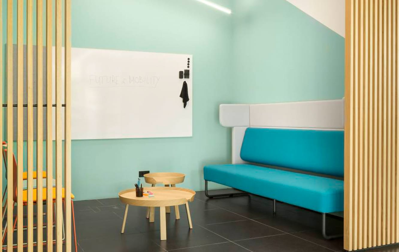 An office with a blue couch and a white board.