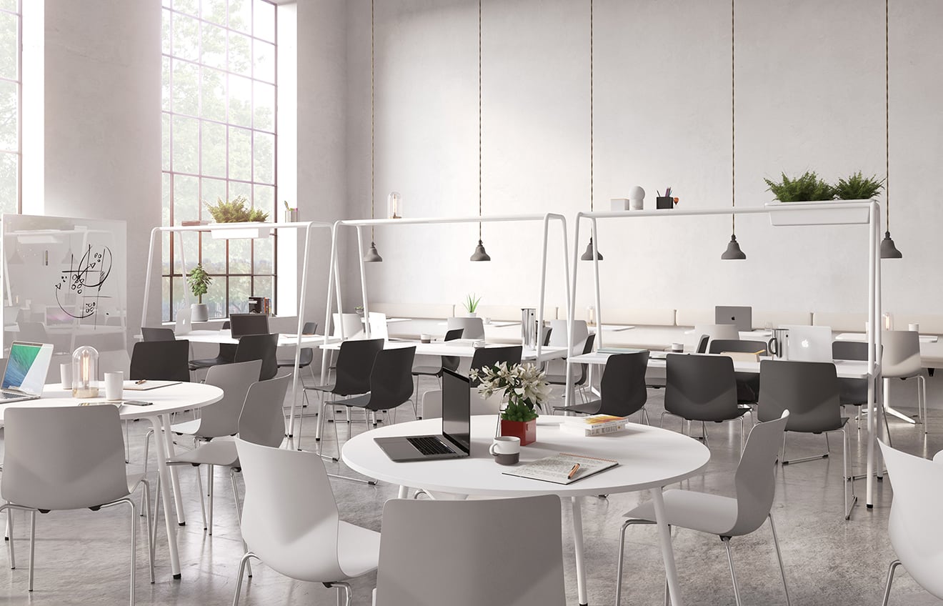 A white and grey office space with community tables and chairs.
