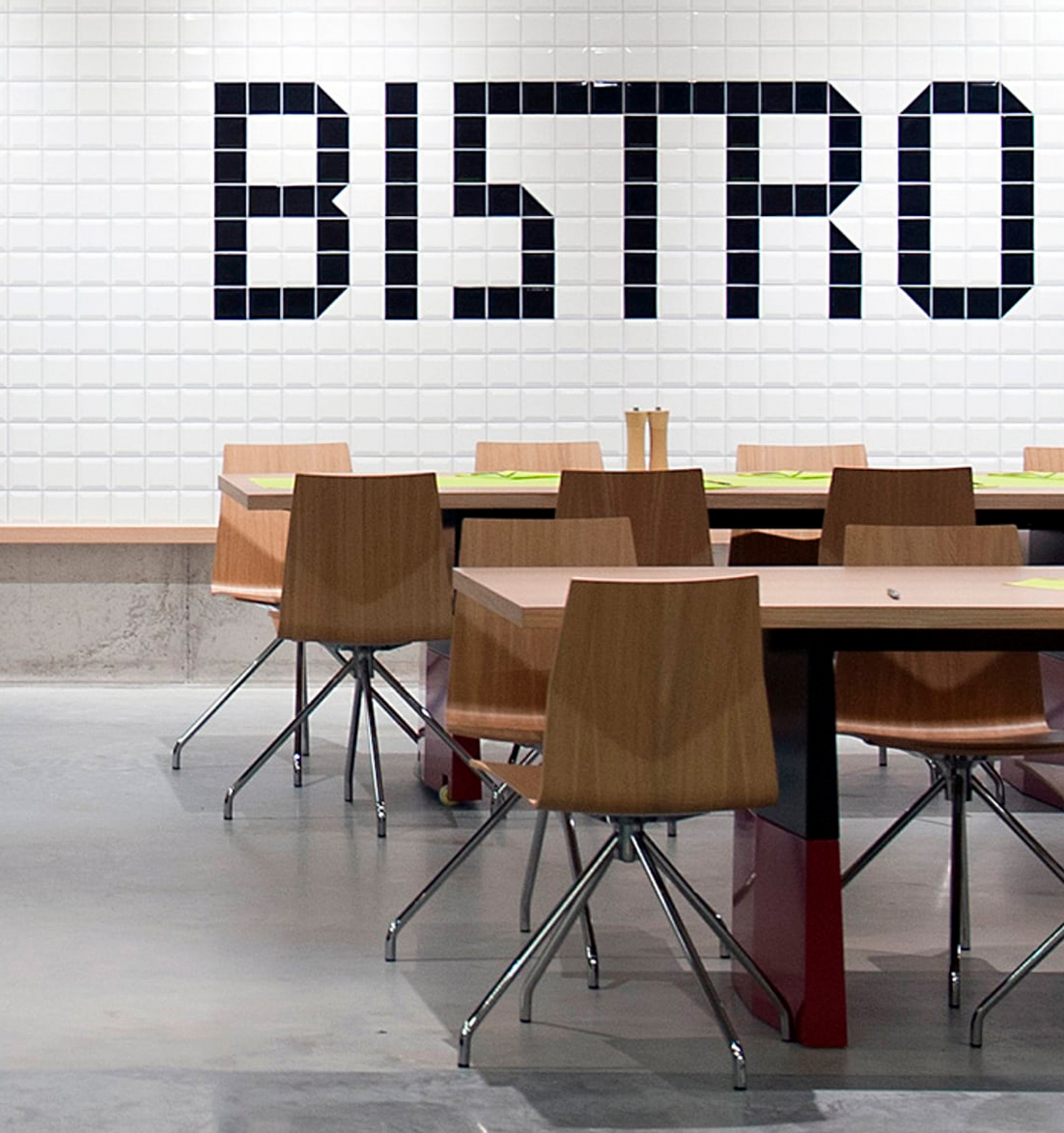 A dining room with canteen furniture such as tables and chairs and a sign that says bistro.