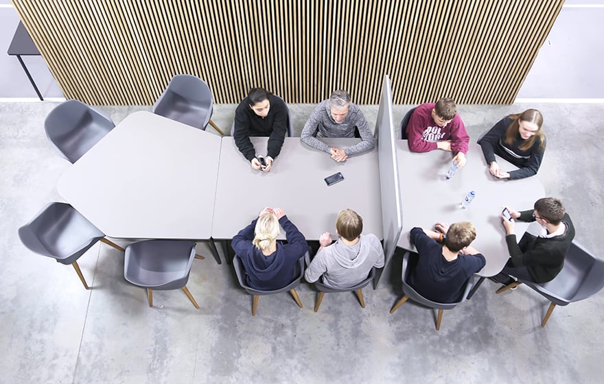 A group of people sitting around a table with office screen dividers