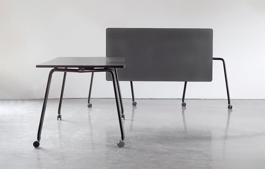 Two black tables on wheels in an empty room.