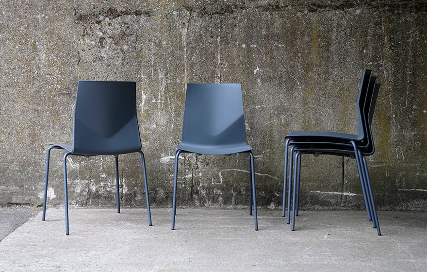 Four blue-grey light weight office chairs against a concrete wall.
