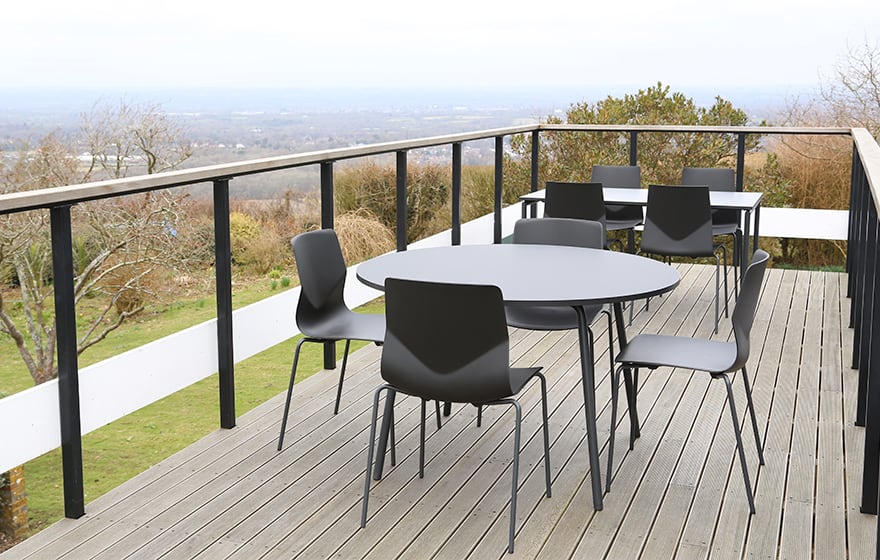 A black table and chairs on a balcony overlooking a view.