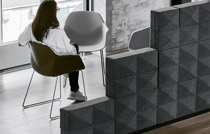 Acoustic panels for offices built into a wall in front of a woman sitting in a chair