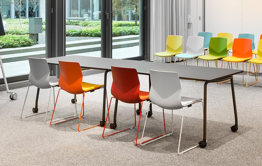 A meeting room with colourful office desk chairs and a table.