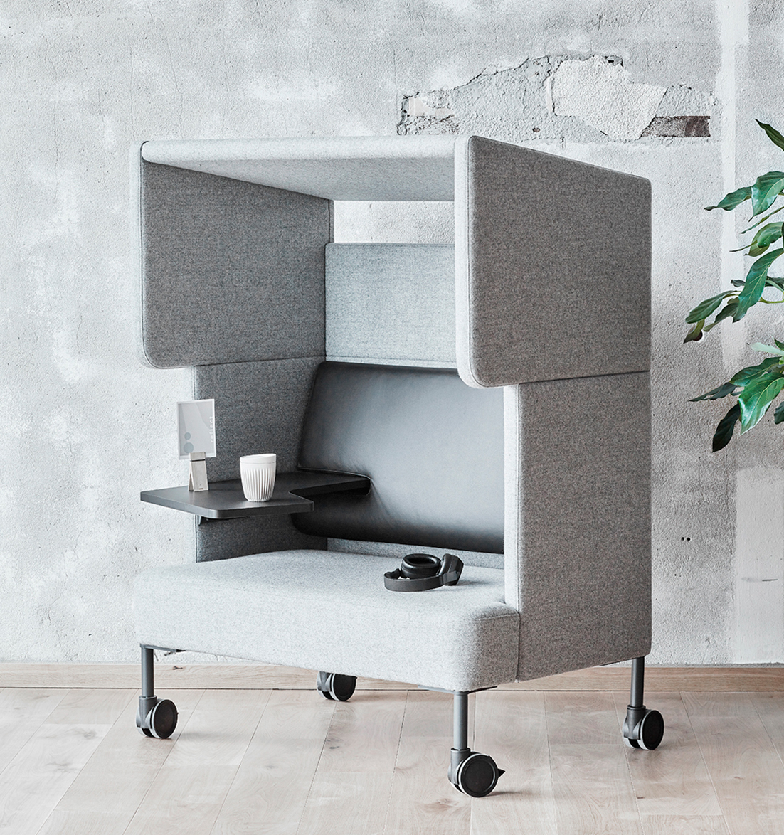 A grey office work booth with a work table and a plant.