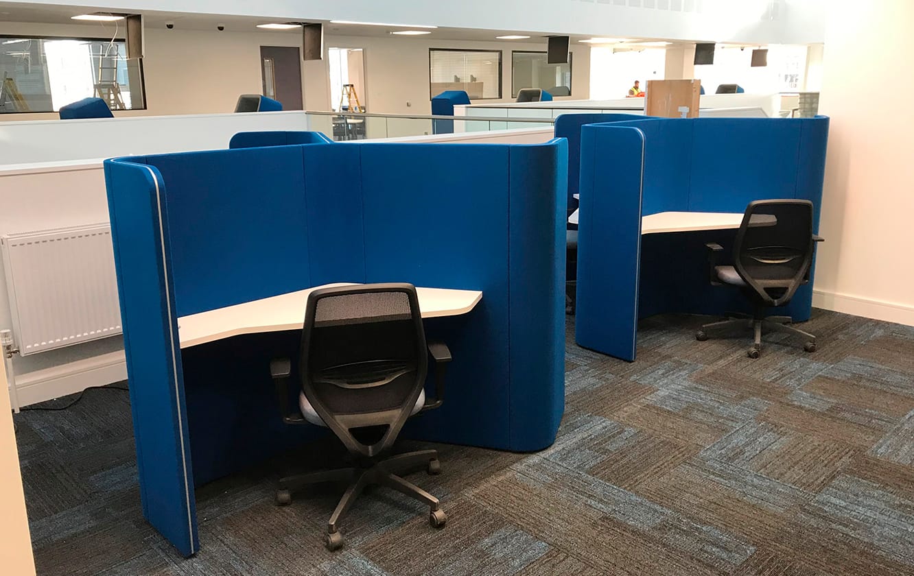 Two blue study booths in an office with desks and chairs.