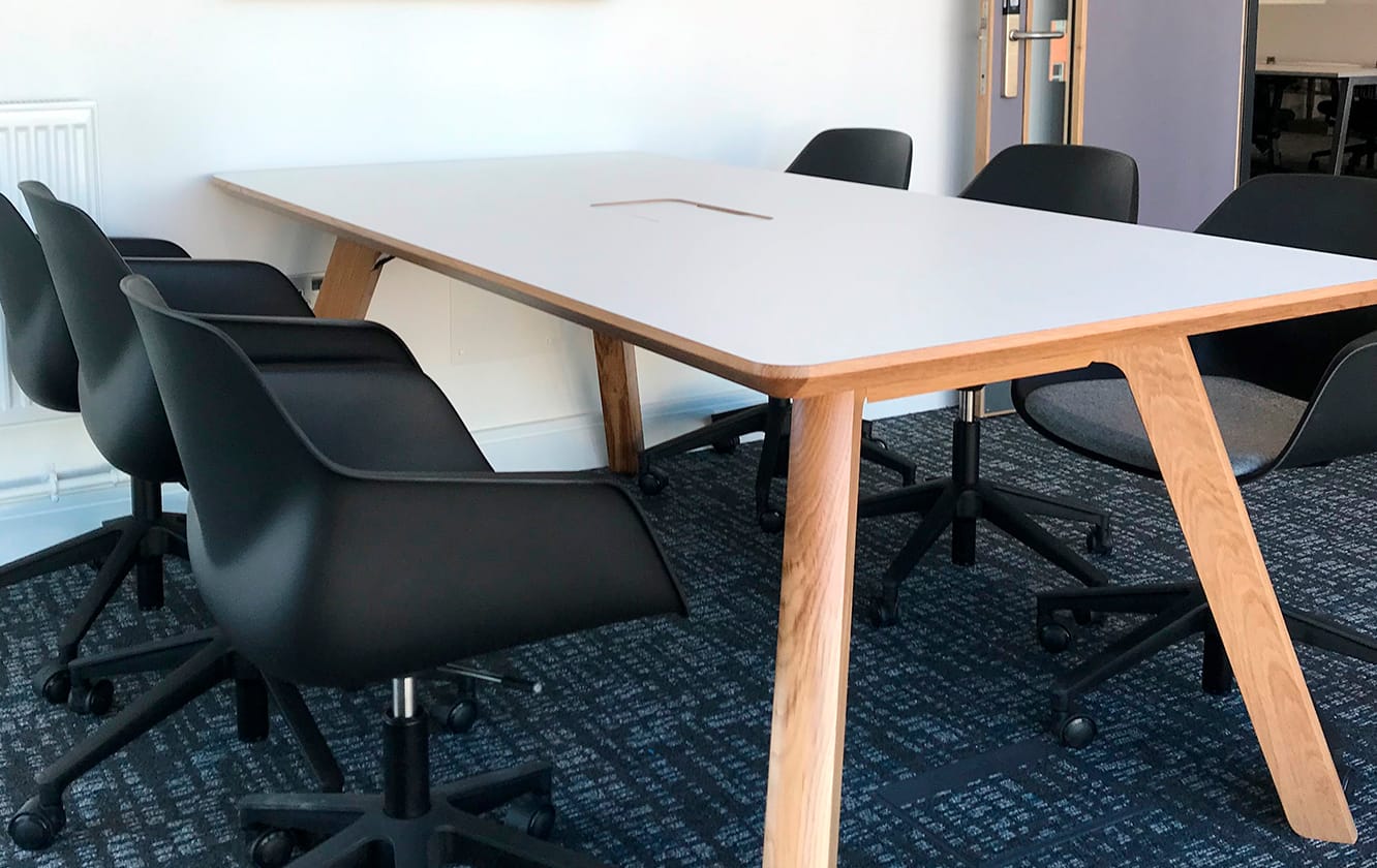 A conference table with wooden legs and chairs in an office.
