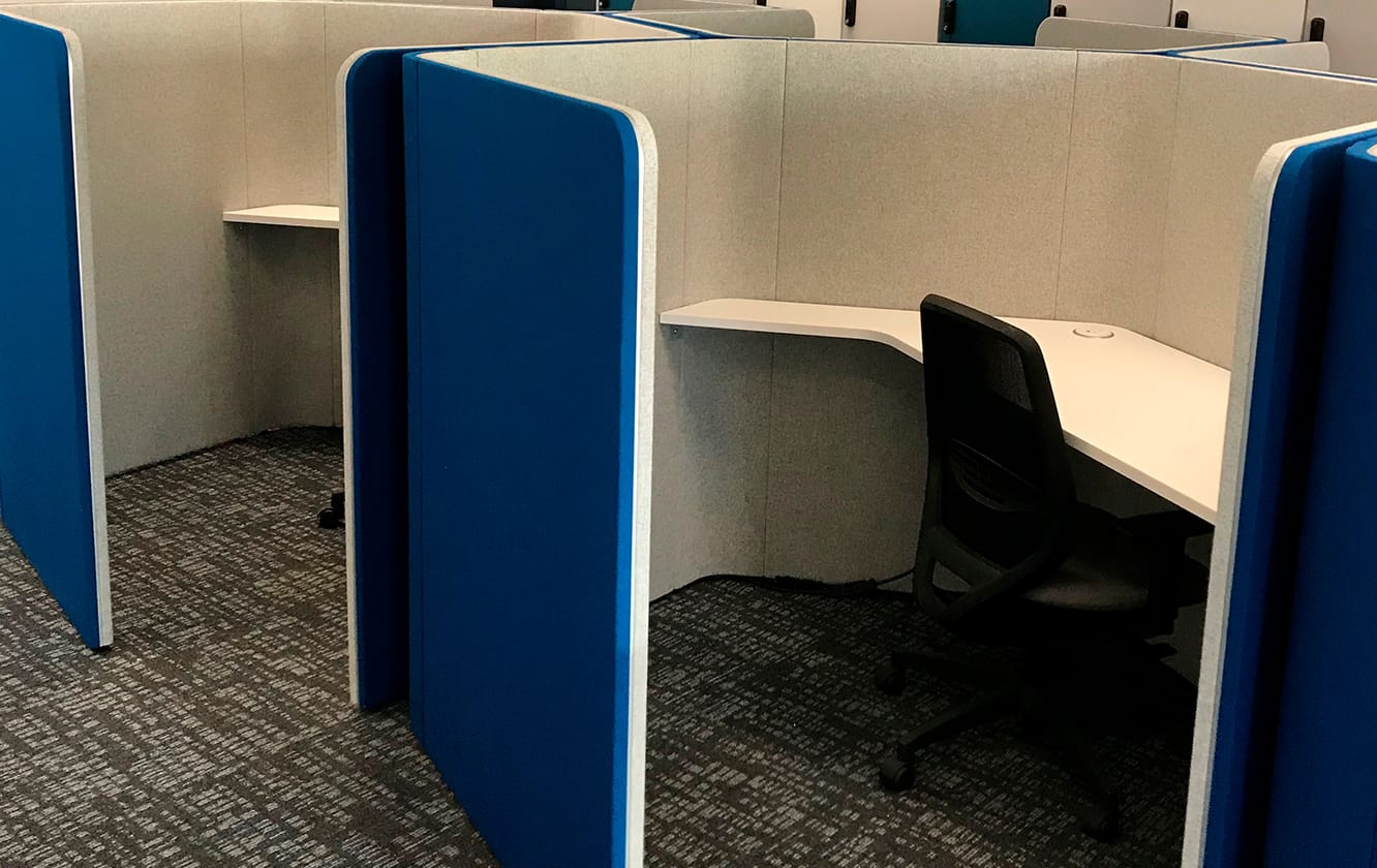A group of blue interconnected honeycomb shaped study booths in an office.