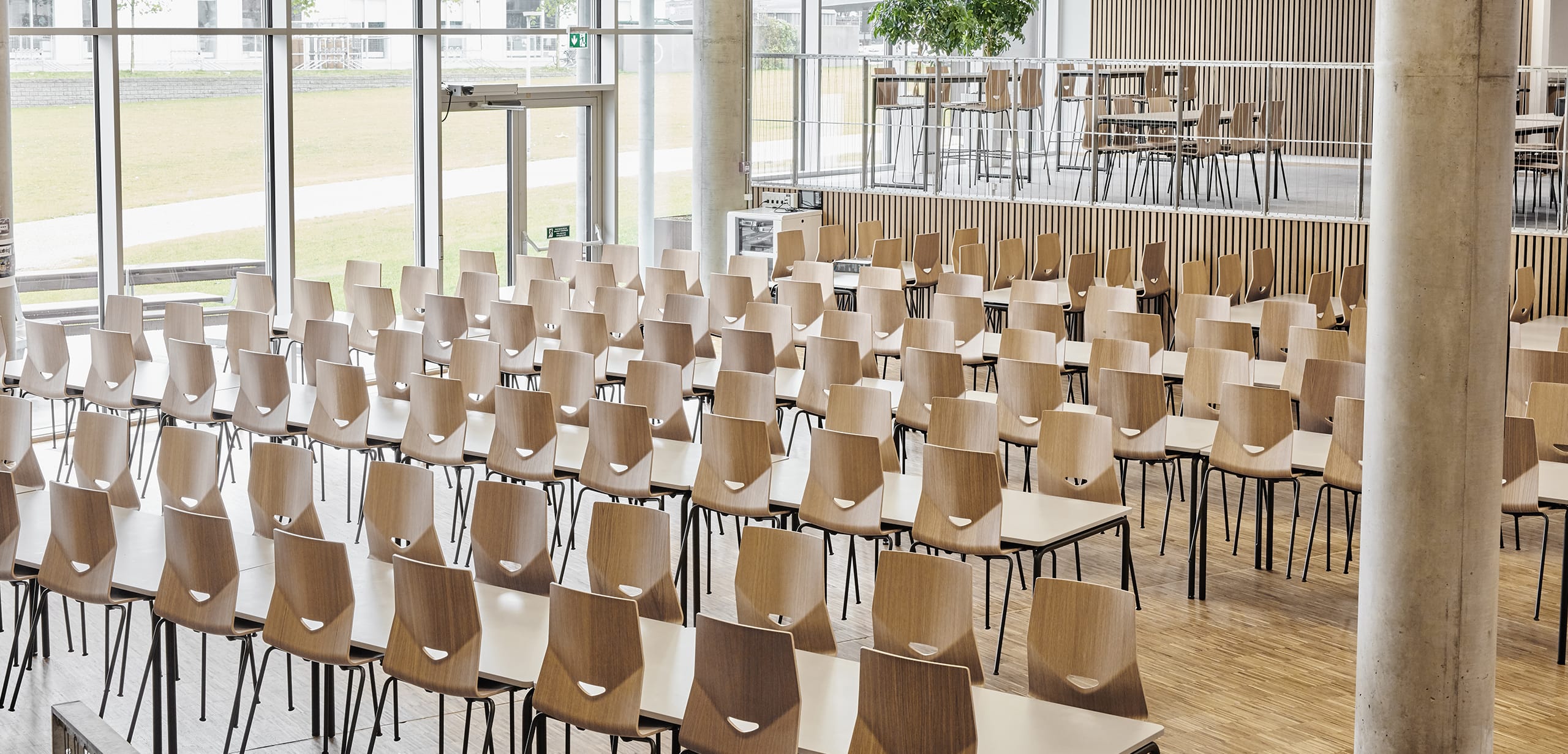 A large conference room with rows of wooden chairs.